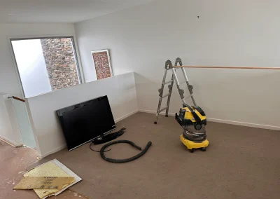 Upstairs living area with old carpet and ladder during prep for renovation at Palm Beach