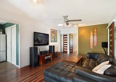 Dated living room with timber floors, ceiling fan and old colour scheme before home renovation at Main Beach