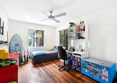 Kid's bedroom with timber floors, blue feature wall and desk area before home renovation at Main Beach