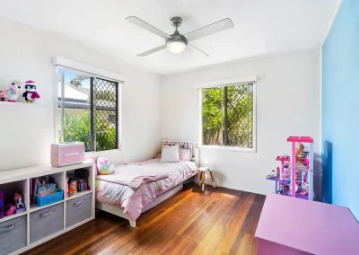 Child's bedroom with ceiling fan and security screens before home renovation at Main Beach