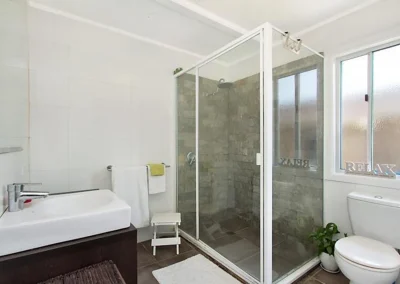 Old bathroom with framed shower screen, bath combo and worn tiles before bathroom renovation at Main Beach