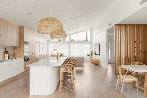 Open-plan kitchen renovation with curved island and timber-look flooring